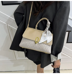Detail of woven texture beige crossbody bag with silk scarf on handle and gold clasp