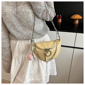 Detail of pale yellow saddle bag with oversized silver ring zippers and chain strap