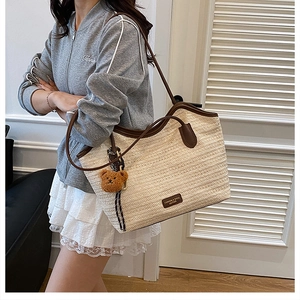 Detail showing the woven texture and brown leather trim of the large straw tote bag