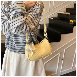 Detail of yellow pleated shoulder bag with pearl lace charm and knot strap design