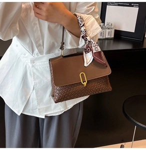 Detail of dark brown woven handbag with gold buckle and decorative silk scarf detail