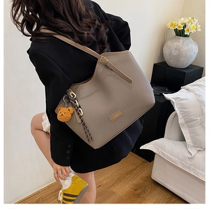 Detailed texture of brown lychee grain leather tote bag with cute yellow bear charm
