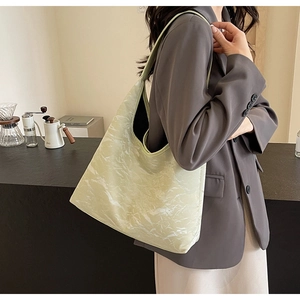 Detailed view of large sage green marble texture tote bag worn by a model in a café setting