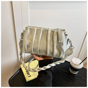 Detailed view of mint green pleated baguette bag with woven handle and gold chain strap