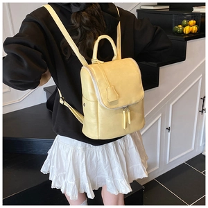 Back view of a model wearing a light yellow PU leather bucket backpack with adjustable straps