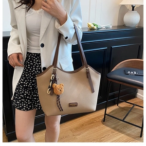 Close-up of beige pebble leather tote with brown straps and cute bear charm detail