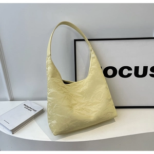 Detail of light yellow hobo bag featuring premium pleated texture and minimalist handle