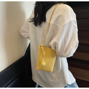 Mini yellow crossbody phone bag with litchi grain texture shown on female model