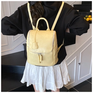 Detail of pale yellow PU leather backpack featuring delicate texture and pendant accessory