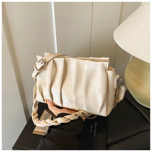Close-up of cream white pleated shoulder bag with adjustable strap and woven handle
