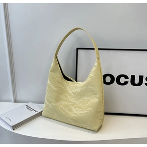 Detail of light yellow hobo bag featuring a unique wrinkled texture and integrated strap