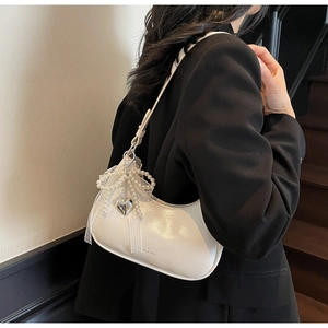 Detailansicht der cremeweißen Mondsichel-Tasche mit Perlenbogen und Herzanhänger