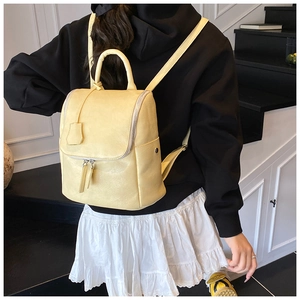 Detail of pale yellow bucket backpack showing smooth PU texture and front zipper pocket
