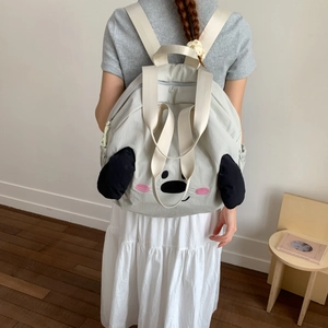 Detail of cute light grey nylon backpack showing cartoon animal face and side pocket