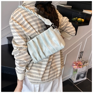 Close-up of light blue pleated underarm bag with woven shoulder strap detail