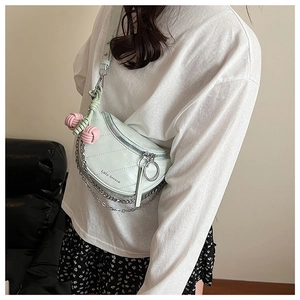 Detail of light green saddle bag with silver chain strap and decorative knot pendant