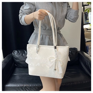 Detail of white tote bag with faux python texture and pearl lace bow accessory