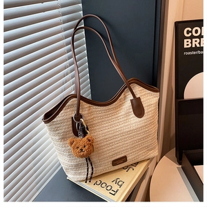 Close-up of woven tote bag with brown leather trim and a cute plush bear charm detail