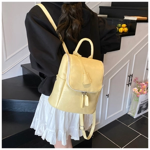 Detail of a minimalist light yellow backpack with arch-top cover and silver zippers