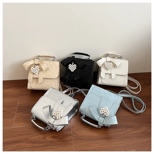 Close-up of five mini bow bags in beige, black, cream, silver and blue with heart charms