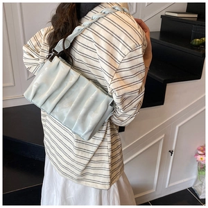 Detail of light blue pleated shoulder bag with matching woven chain strap on model