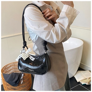 Black patent leather cloud bag with lace bow and pearl heart charm detail shown on model
