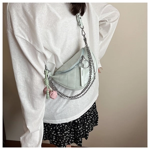 Detail of light green crescent saddle bag with quilted texture and silver chain strap