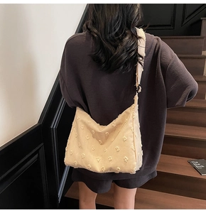 Close-up of beige canvas hobo bag with 3D floral tufting texture and wide shoulder strap