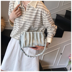 Detail of light blue pleated handbag with woven handle and silver chain strap