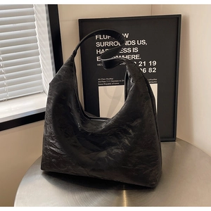Detail of black large hobo bag featuring crinkled leather texture and wide shoulder strap