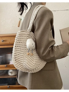 Beige hollow woven tote bag with cute cloud pendant on model in a minimalist setting
