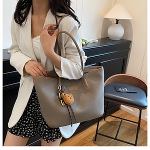 Dettaglio borsa tote in pelle color talpa con un grazioso ciondolo a forma di orso