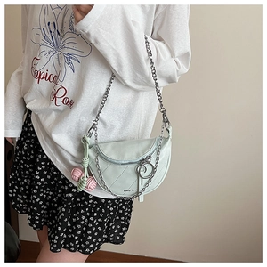 Detail of light green quilted saddle bag with silver chain and woven ball charm