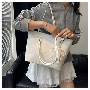 Detailed view of white snakeskin tote bag with lace bow and pearl charm decoration