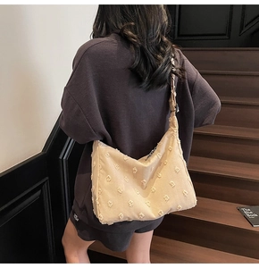 Detailed shot of beige large canvas tote with 3D floral texture and wide strap on a model