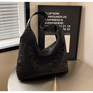 Detail of black pleated faux leather tote bag on metal table with modern minimalist decor