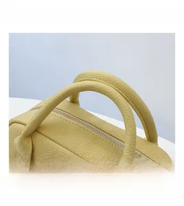 Detail of yellow lychee grain leather bag with silver zipper and dual handles