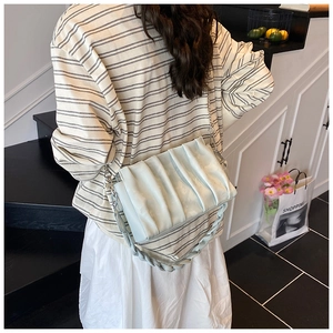 Detail view of mint green pleated crossbody bag with metal chain strap and woven detail
