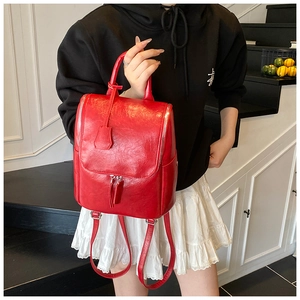 Close-up of vibrant red leather backpack featuring silver zippers and tassel details