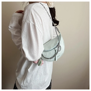 Detail of mint green quilted saddle bag with silver chain and woven ball charm decoration