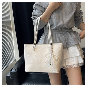 Detail shot of large cream tote bag with snake skin texture and pearl lace bow charm