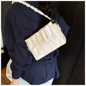 Detail of cream pleated shoulder bag with woven strap shown on model's shoulder