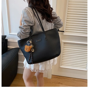 Dettaglio della borsa tote in pelle martellata nera con spalline e ciondolo a orso