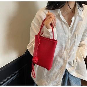 Detail of red pebbled leather mini bag featuring unique double knotted handle decoration