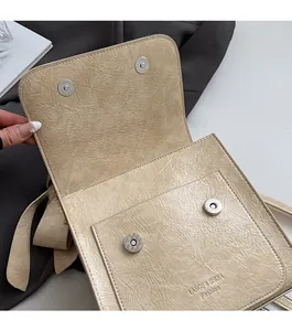 Detail of beige wrinkled leather bag showing secure double magnetic snap closures