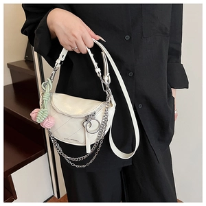 Detail of white quilted saddle bag with silver chain and decorative knot pendants
