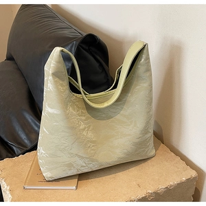 Detail of pistachio green tote bag featuring textured pleated fabric on a stone pedestal