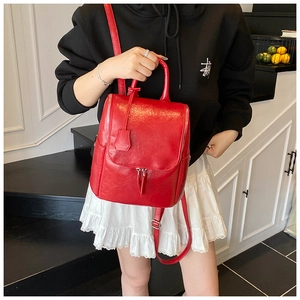 Close-up of a glossy red faux leather backpack with vertical zippers and top handle