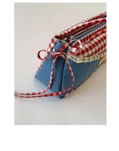 Detail of blue denim cosmetic bag with red gingham trim and white lace edges