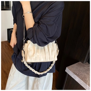 Detail view of cream pleated bag with silver chain strap and woven top handle